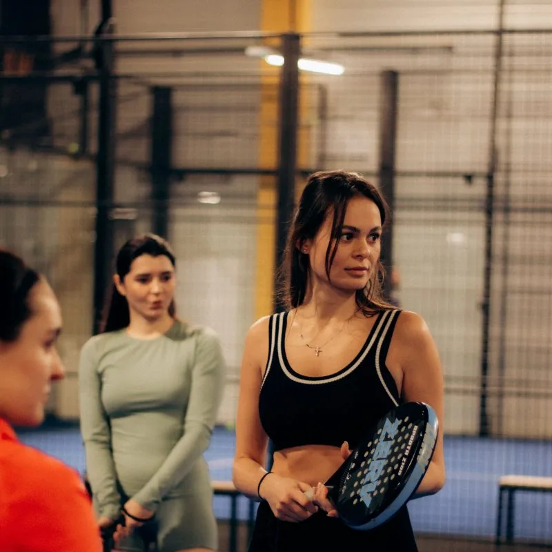 Padeltrainer geeft uitleg aan een groepje spelers